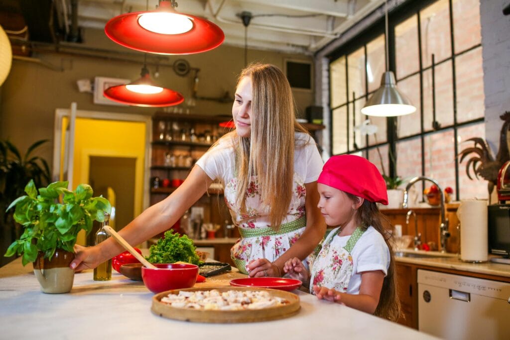 Mother and daughter enjoying cooking together in a cozy rustic kitchen setting.