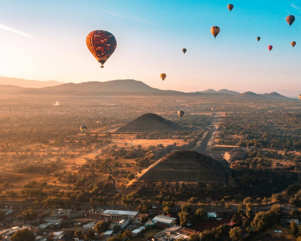 Beautiful aerial view of hot air balloons flying over Teotihuacán, Mexico at sunrise.