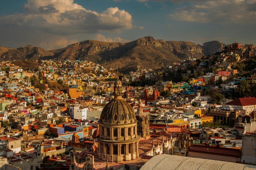 A vibrant aerial view of Guanajuato City showcasing colorful architecture and mountainous backdrop.