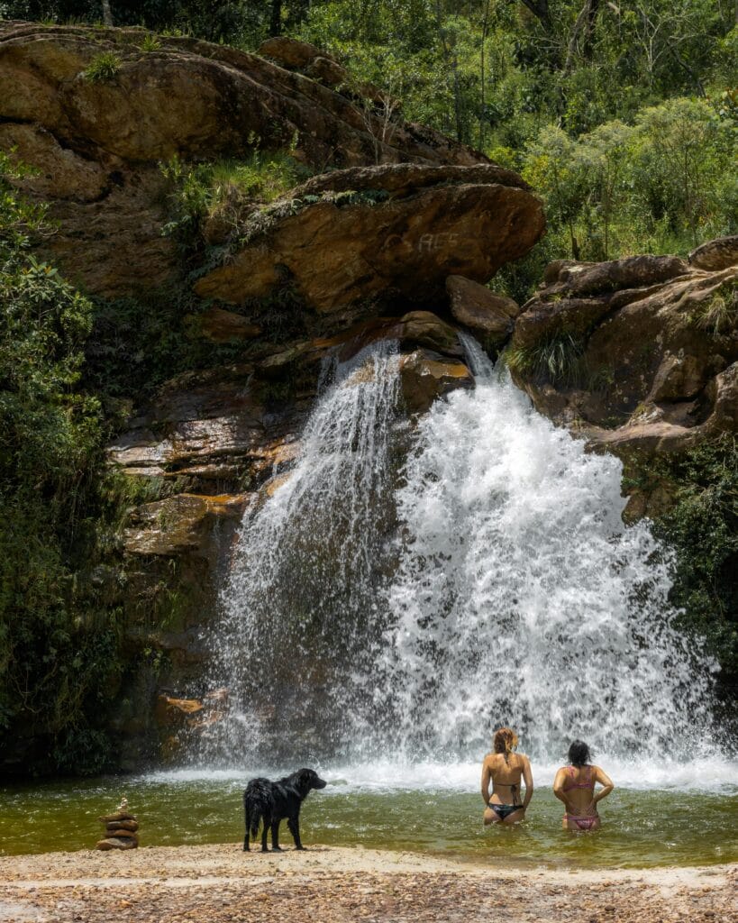 pexels-photo-29838199-29838199 Two adults relax by a waterfall with a dog in Ouro Preto, Brazil's natural setting.