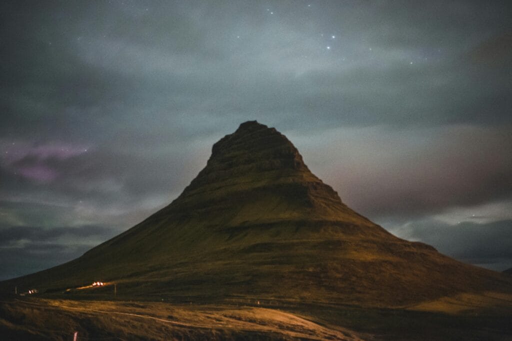 Stunning view of Kirkjufell mountain under twilight skies in Iceland's dramatic landscape.