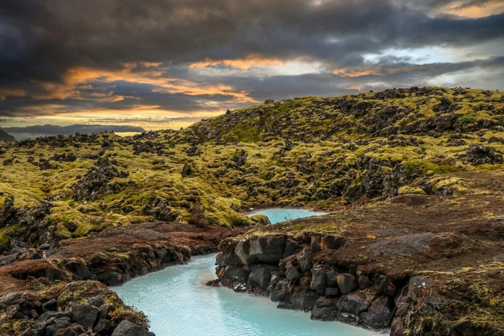 Captivating views of Iceland's dramatic landscape featuring a blue lagoon and rugged terrain under dark clouds.
