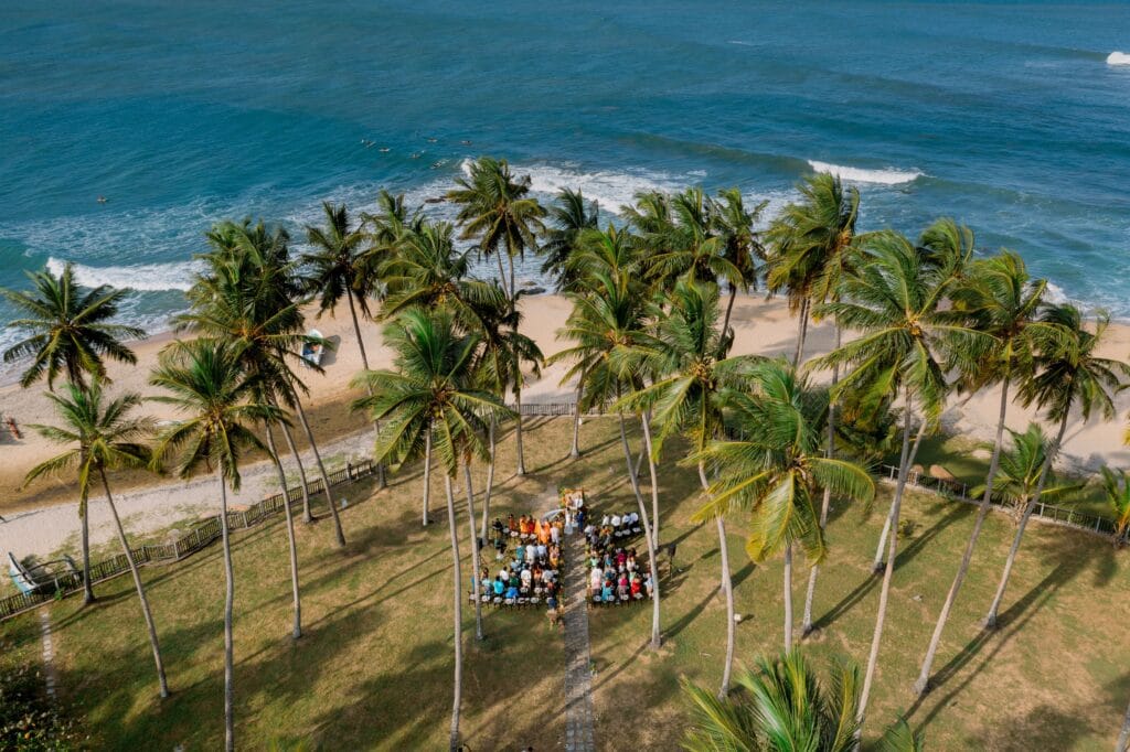Stunning aerial view of a tropical beachside ceremony among palm trees at Arugam Bay, Sri Lanka.