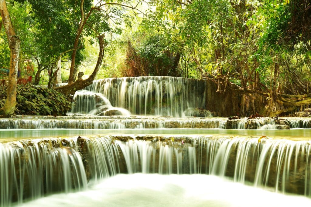 Tranquil waterfall cascading through lush greenery in Luang Prabang, Laos.